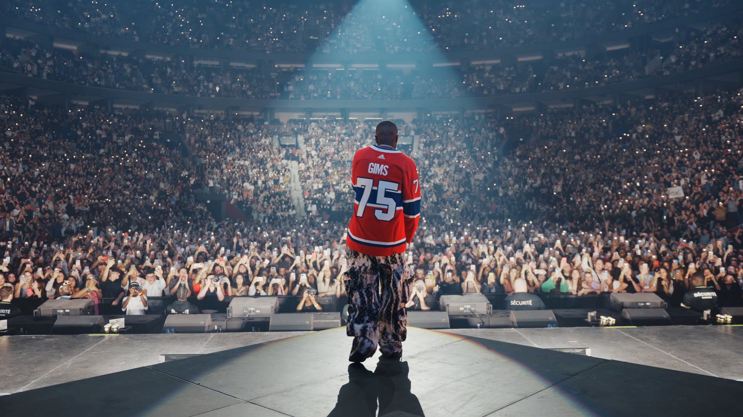 Artist alone in the spotlight in front of a packed arena — filmed by Wolf