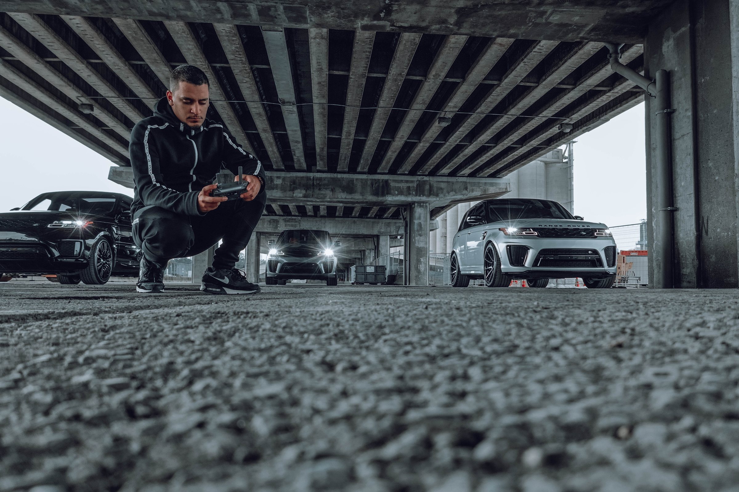 Wolf flying a drone low in front of a fleet of luxury cars