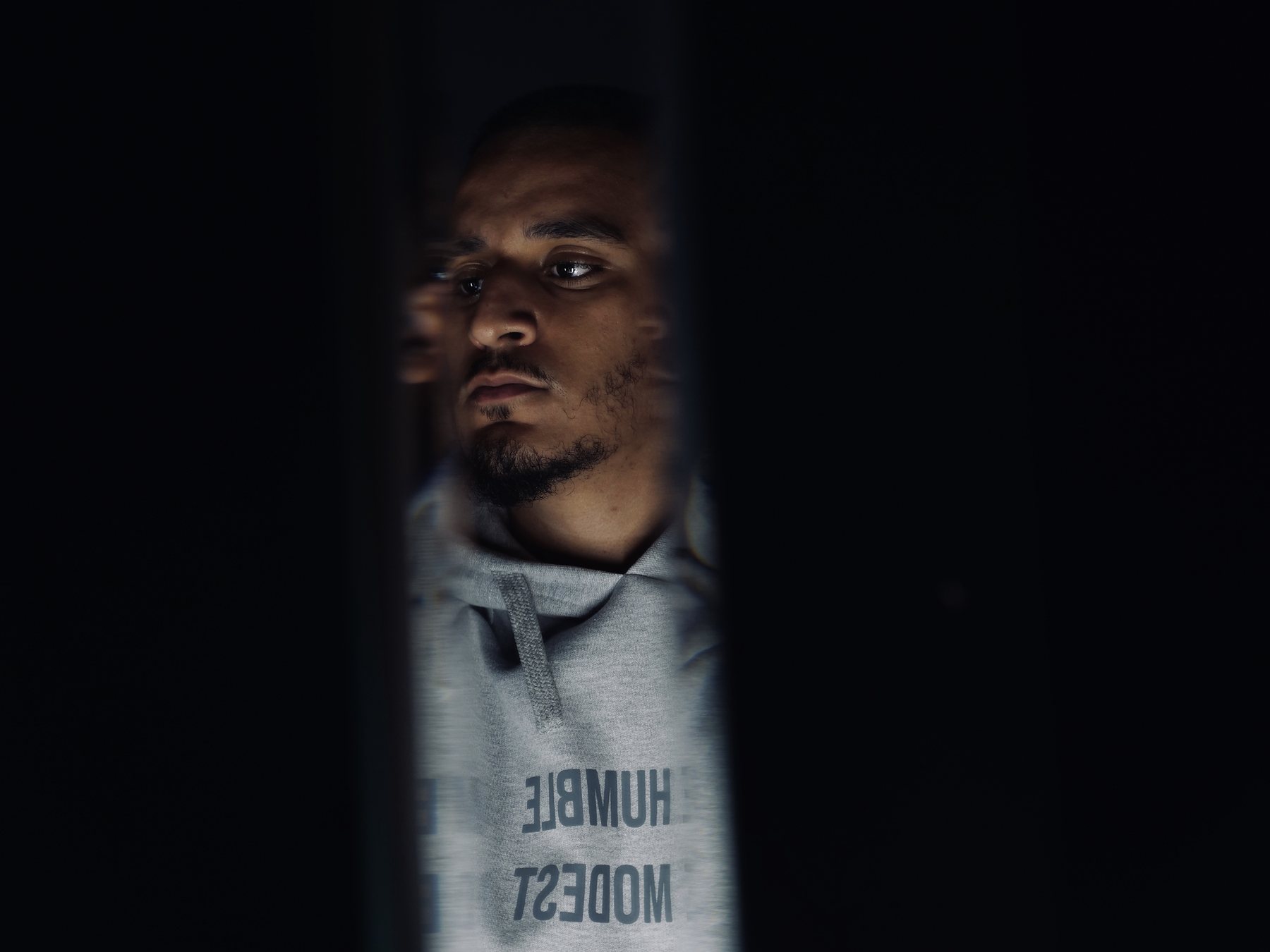 Wolf's face half-hidden in shadow, HUMBLE MODEST written on his hoodie