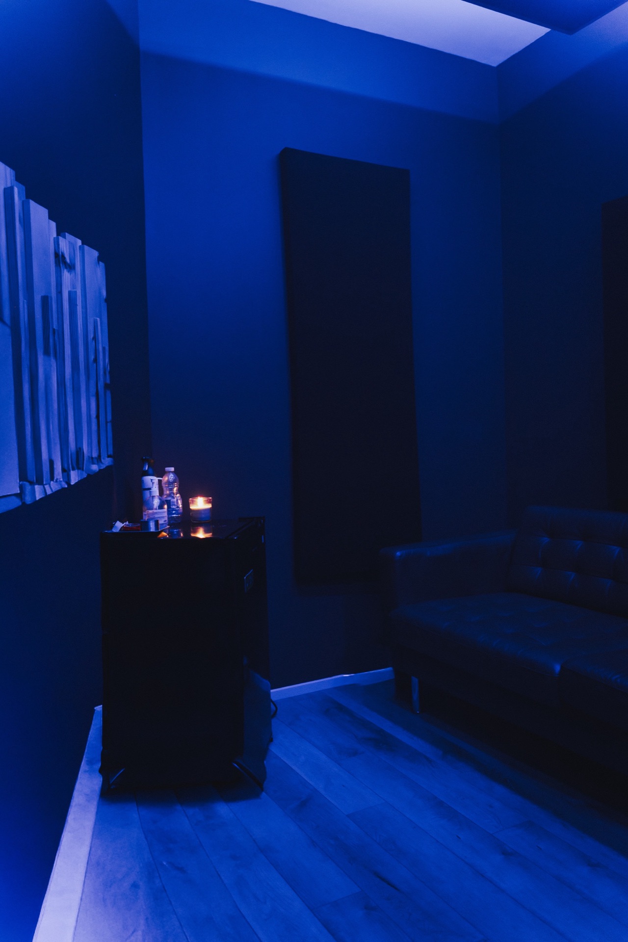 Studio lounge at night — soft blue light, leather couch, candle